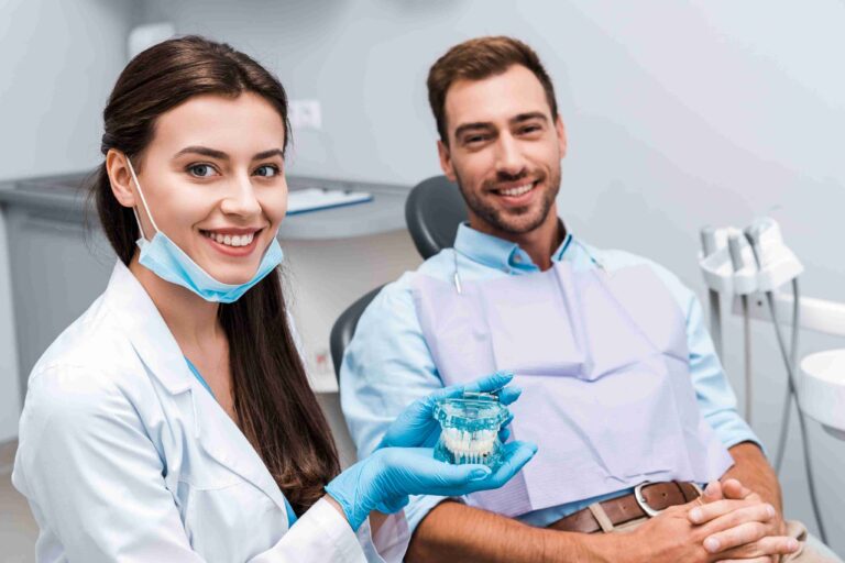 Dentist showing a dental model to a smiling patient.